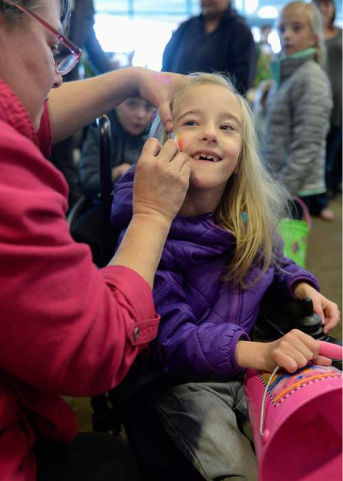 Francisco Kjolseth | The Salt Lake Tribune
Sharon Neilson of Changing Faces, paints an Easter egg on the cheek of Audrey Sterner, 8, before an egg hunt. Shriners Hospitals hosted an Easter Egg Hunt adapted for patients with physical challenges. Around 100 patients and their families attended Wednesday's annual Easter Egg Hunt, which gave children with physical challenges who may be in wheelchairs or rely on the assistance of a walker, the space, time and support they needed to enjoy the Spring time tradition.