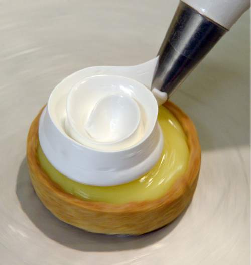 Al Hartmann  |  The Salt Lake Tribune
Meringue is squeezed from a pastry bag to decorate the top of Meyer lemon tarts.