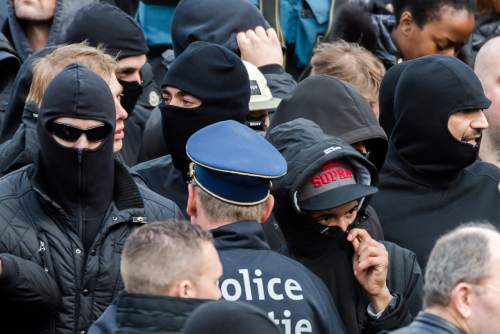 Right wing demonstrators talk with a police man as they protest at a memorial site at the Place de la Bourse in Brussels, Sunday, March 27, 2016. In a sign of the tensions in the Belgian capital and the way security services are stretched across the country, Belgium's interior minister appealed to residents not to march Sunday in Brussels in solidarity with the victims. (AP Photo/Geert Vanden Wijngaert)