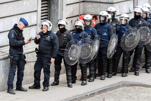 Riot police line up as right wing demonstrators protest at a memorial site at the Place de la Bourse in Brussels, Sunday, March 27, 2016. In a sign of the tensions in the Belgian capital and the way security services are stretched across the country, Belgium's interior minister appealed to residents not to march Sunday in Brussels in solidarity with the victims. (AP Photo/Geert Vanden Wijngaert)