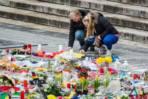 Two women read a solidarity message at floral tributes at a memorial site at the Place de la Bourse in Brussels, Sunday, March 27, 2016. In a sign of the tensions in the Belgian capital and the way security services are stretched across the country, Belgium's interior minister appealed to residents not to march Sunday in Brussels in solidarity with the victims. (AP Photo/Geert Vanden Wijngaert)