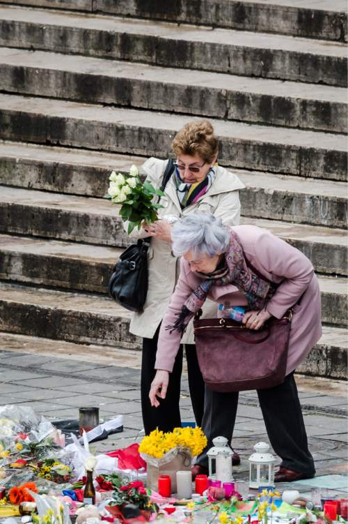 Two women lay flowers at floral tributes at a memorial site at the Place de la Bourse in Brussels, Sunday, March 27, 2016. In a sign of the tensions in the Belgian capital and the way security services are stretched across the country, Belgium's interior minister appealed to residents not to march Sunday in Brussels in solidarity with the victims. (AP Photo/Geert Vanden Wijngaert)
