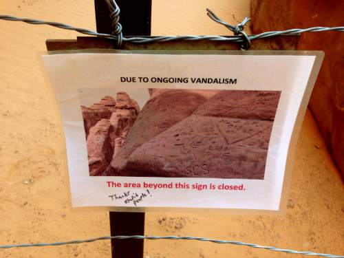 Erin Alberty  |  Tribune file photo
A sign displays the consequence of vandalism on ancient rock formations near Sand Dune Arch in Arches National Park.
