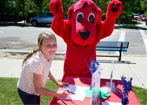 Scott Sommerdorf   |  The Salt Lake Tribune  
"Clifford The Big Red Dog" celebrates the picture Lilli Durham, 10, drew at the Scholastic "Summer Reading Road Trip" pop-up book festival at the King's English Bookshop in Salt Lake City on Wednesday.