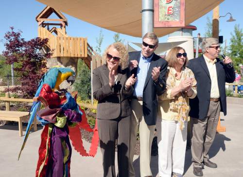 Al Hartmann  |  The Salt Lake Tribune
Salt Lake Mayor Jackie Biskupski, left, applauds with James Hogle, Jr, Hogle Zoo Chairman, Karen Hale, Associate Chief Administrative Officer of Salt Lake County Mayor McAdams office, and Hogle Zoo Director Craig Dinsmore watching an unusual ribbon cutting Thursday May 12.  Bo" a Blue-Gold Macaw picks apart a ribbon to open Creekside, a new playgound attraction that includes tree house elements, slides, spider web netting, swinging vines and rickety bridges.  The new space also features Wyatt Fricks Discovery Theater, where children get up close with small animals, Lighthouse Point Splash Zone, and Creekside boardwalk for a shady pathway walk above Emmigration Creek.