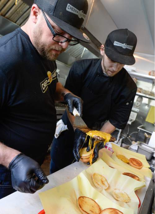Francisco Kjolseth | The Salt Lake Tribune 
Chedda Burger owner Nick Watts, left, assembles burgers with the help of Leigh Smith during a recent lunch rush.