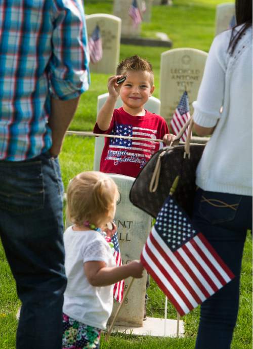 Steve Griffin  |  The Salt Lake Tribune
Becky Clark and husband, Jeff, take photos of the children Brinley and Mason as they eat Oreo cookies at the grave of her father, Air Force Maj. A. Brent Merrill, as Fort Douglas hosts its annual Memorial Day observance at the cemetery in Salt Lake City, Monday, May 25, 2015.