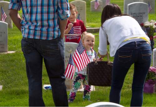 Steve Griffin  |  The Salt Lake Tribune
Becky Clark and husband, Jeff, take photos of the children Brinley and Mason as they eat Oreo cookies at the grave of her father, Air Force Maj. A. Brent Merrill, as Fort Douglas hosts its annual Memorial Day observance at the cemetery in Salt Lake City, Monday, May 25, 2015.