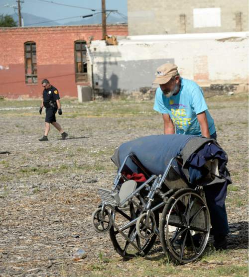 Al Hartmann  |  Tribune file photo
Homeless man with belongings on his wheelchair makes his way across lot posted no tresspassing at 500 W. and 350 S. as a Salt Lake Policeman patrols the area.