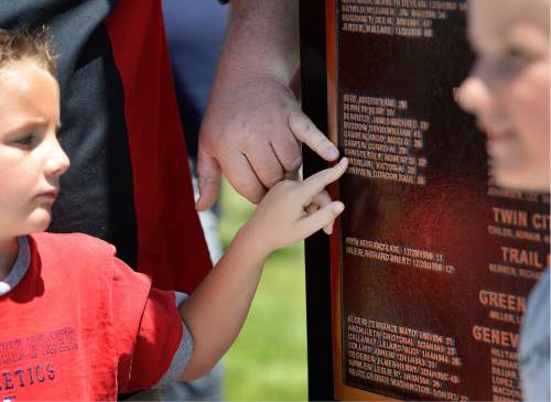 Scott Sommerdorf   |  The Salt Lake Tribune  
Six year old Anthony Cingolani touches the name of his grandfather Victor Cingolani, who lost his life in the Wilberg mining disaster. The names of miners lost, adorn the new Miners Memorial in Castle Dale.