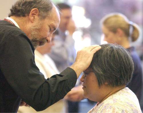 Ryan Galbraith  |  Tribune File Photo
The Rev. Lincoln Ure, chaplain at St. Mark's Hospital, blesses Stephanie Mori-Nakao (a nurse at the hospital) at a "Blessing of the Hands" service in 2002.