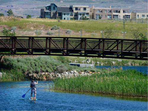 Scott Sommerdorf   |  The Salt Lake Tribune  
A man paddle boards on the pond at the Daybreak community near South Jordan, Friday, June 17, 2016.