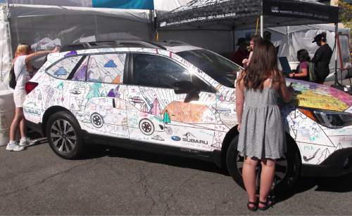 Sean P. Means  |  The Salt Lake Tribune

Attendees at the 2016 Utah Arts Festival add their own graffiti to a car, donated by a festival sponsor, parked on 200 East.
