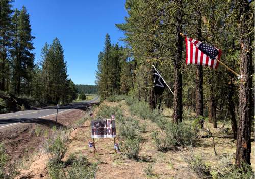 In this June 21, 2016 photo, a sign for Camp Freedom built in the Malheur National Forest marks the spot across a highway from where LaVoy Finicum was killed near Burns, Ore.  Winter and spring have passed since an armed occupation of a federal wildlife refuge ended in Oregon, but aftershocks of the takeover are still hitting this high desert region. (AP Photo/Andrew Selsky)