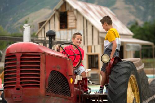 Leah Hogsten  |  The Salt Lake Tribune
Mason Redding, 11, (right) and his cousin enjoy playing on an old farm tractor during the ribbon cutting at Wheadon Farm Regional Park, Wednesday, June, 29, 2016 in Draper. The large farm-themed park features a play barn, a climbing haystack, and a hay derrick.
Wheadon Farm Regional Park is one of three regional parks funded by the $47 million Park Bond, authorized by voters in 2012. The Gene and Deane Wheadon farm was a working farm from the early 1900s to 1997, when a conservation easement was placed on the property by the Wheadon family. The 64-acre farm was purchased by Salt Lake County with the 2006 Open Space Bond and master-planned 2008.  Phase I of the park will be constructed.