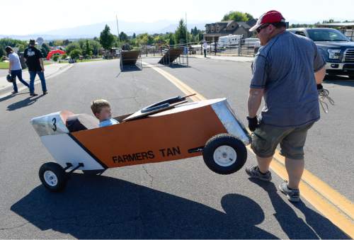 Francisco Kjolseth | The Salt Lake Tribune
Evan Williams, 10, gets his "Farmer Tan" racer put into position by his dad Caleb as kids compete in the 6th annual American Fork Gravity Soap Box Derby on Thursday July 7th, 2016.