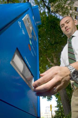 Tribune file photo
 Chad Golsan, of Salt Lake City, reaches for his parking receipt from  a parking kiosk on Main Street last year.