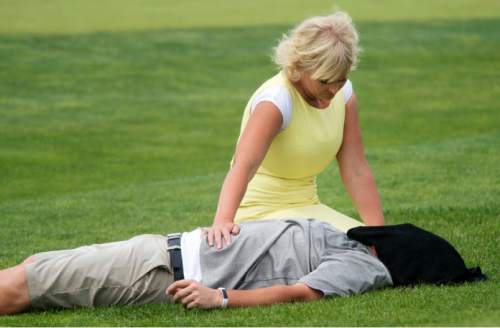 Steve Griffin / The Salt Lake Tribune

Jennica Smith rests her hand on her husband Aaron Smith as he lays on his back with a wet towel over his face after he couldn't continue after the 11th hole of his semifinal match against Kyler Dearden in the 118th annual Utah State Amateur golf tournament  at Alpine Country Club in Alpine, Utah Friday July 15, 2016. Smith laid down on the grass after putting out on the hole complaining of back spasms and exhaustion and was taken to the hospital by ambulance.