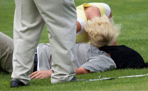 Steve Griffin / The Salt Lake Tribune

Jennica Smith rests her head on her husband Aaron Smith as he lays on his back with a wet towel over his face after he couldn't continue after the 11th hole of his semifinal match against Kyler Dearden in the 118th annual Utah State Amateur golf tournament  at Alpine Country Club in Alpine, Utah Friday July 15, 2016. Smith laid down on the grass after putting out on the hole complaining of back spasms and exhaustion and was taken to the hospital by ambulance.