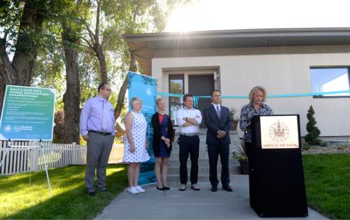 Al Hartmann  |  The Salt Lake Tribune 
Mayor Jackie Biskupski, right, with Salt Lake City housing officials speak before cutting the ribbon on Thursday, July 21st at the Emery Passive House ñ a model of efficient, innovative, and affordable family housing in Salt Lake Cityís Poplar Grove neighborhood.
The event launched launch the new Housing Innovation Lab, a project of Salt Lake Cityís Housing and Neighborhood Development Division (HAND). This community-based effort is built on the premise that homes can be well-built with popular design features while still being affordable. The lab will advance innovation in affordable housing design, quality construction, and finance through education, collaboration, and experimentation.
The 2,100-square-foot Emery Passive House behind them features cutting-edge design and construction, with four bedrooms, 2.5 baths, a two-car garage, a fully fenced yard, and a contemporary exterior. The house will operate on one-sixth the energy required to heat a standard home.