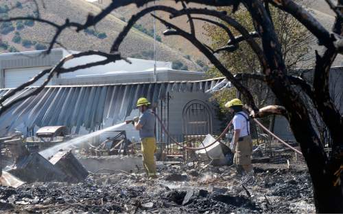 Al Hartmann  |  The Salt Lake Tribune 
Firefighters work to put out hot spots in a burned out neighborhood in Tooele, Utah, on Wednesday, July 20, 2016. Wind whipped up a grass fire that eventually destroyed 10 homes.