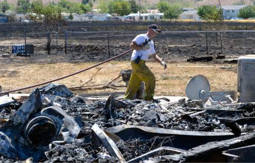 Al Hartmann  |  The Salt Lake Tribune 
Firefighters work to put out hot spots in a burned out neighborhood in Tooele, Utah, on Wednesday, July 20, 2016. Wind whipped up a grass fire that eventually destroyed 10 homes.