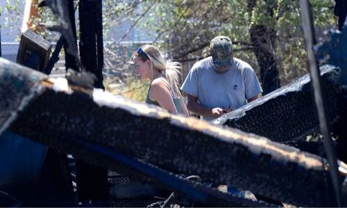 Al Hartmann  |  The Salt Lake Tribune 
Tooele residents survey damage at a burned out neighborhood on Wednesday, July 20, 2016. Wind whipped up a grass fire that eventually destroyed 10 homes.