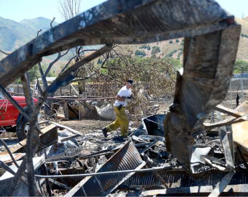 Al Hartmann  |  The Salt Lake Tribune 
Firefighters work to put out hot spots in a burned out neighborhood in Tooele, Utah, on Wednesday, July 20, 2016. Wind whipped up a grass fire that eventually destroyed 10 homes.