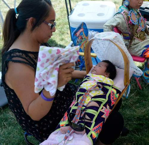 Al Hartmann  |  The Salt Lake Tribune 
Cindra Robinson, from Montezuma Creek, UT fans her 1-month-old duaghter Kaliyah in the shade at the annual Native American Celebration July 25 at Liberty Park.