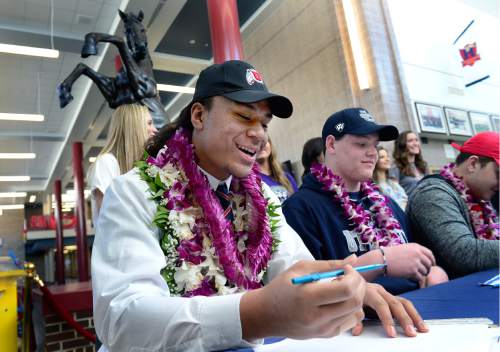 Scott Sommerdorf   |  The Salt Lake Tribune
Herriman defensive end Leki Fotu, left, signs his name during a ceremony when he announced that he's committed to play football at the University of Utah, Wednesday, February 3, 2016. At right is team mate Ty Shaw, (OL), who committed to Utah State.