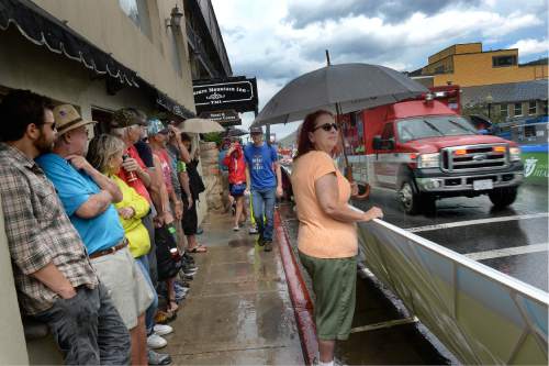 Scott Sommerdorf   |  The Salt Lake Tribune  
Race fans huddle under whatever cover they can find as the Tour of Utah starts with a sudden downpour on Park City's Main Street, Sunday, August 7, 2016.