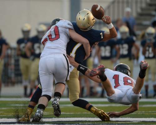 Francisco Kjolseth | The Salt Lake Tribune
Skyline quarter back George Weeks takes a hard hit from behind by Hurricane players Holt Porter, left, and Alan Madsen in game action at Skyline on Thursday, Aug. 20, 2015.