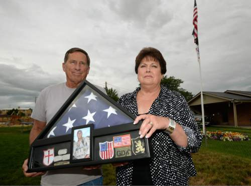 Al Hartmann  |  The Salt Lake Tribune 
Betty and Rodney Workman of Blanding hold a case of dog tags, Marine patches and the American flag that honored their son Jason who was buried with honors at Arlington Cemetery.  Jason Workman, a member of Seal Team 6 was among 38 military personnel shot down by Taliban fighters in a Chinook helicopter on Aug. 6, 2011. It was the largest loss of U.S. life in the Afghanistan campaign.  Two Utahns were on the helicopter,  Taylorsville's Jared Day and Blanding's Jason Workman. Five years later, family and friends still grapple with their absence while battling to keep alive their memory -- Workman, as a big, daring family man with a kind heart and Day as a "goofball" who loved video games and anime and who could make people laugh during times of extreme stress.
The two men shared a birthday, Aug. 12.