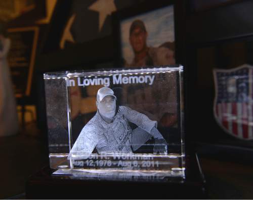 Al Hartmann  |  The Salt Lake Tribune 
Three dimensional glass engraved image of Jason Workman that sits in Betty and Rodney Workman's living room in Blanding. Jason Workman, a member of Seal Team 6 was among 38 military personnel shot down by Taliban fighters in a Chinook helicopter on Aug. 6, 2011. It was the largest loss of U.S. life in the Afghanistan campaign.  Two Utahns were on the helicopter,  Taylorsville's Jared Day and Blanding's Jason Workman. Five years later, family and friends still grapple with their absence while battling to keep alive their memory -- Workman, as a big, daring family man with a kind heart and Day as a "goofball" who loved video games and anime and who could make people laugh during times of extreme stress.
The two men shared a birthday, Aug. 12.