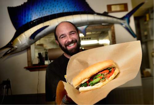 Scott Sommerdorf   |  The Salt Lake Tribune  
Este Deli owner Dave Heiblim holds the roast pork with broccoli rabe sandwich in front of the Sailfish he caught as a 10 year old at Este Deli.