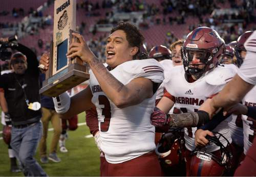 Scott Sommerdorf   |  The Salt Lake Tribune
Herriman's Noah Vaea (3) parades around with the 5A trophy after Herriman won the Utah 5A championship 17-14 over Lone Peak, Friday, November 20, 2015.