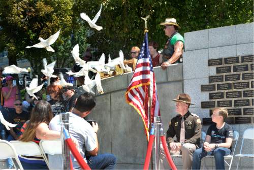 Scott Sommerdorf   |  The Salt Lake Tribune  
UHP Colonel Michael Rapich, left, and Jack Barney the son of fallen officer Doug Barney, watch as doves are released at the end of the pinning ceremony at the Utah Law Enforcement Memorial following the "Ride for the Fallen",  Sunday, August 21, 2016.