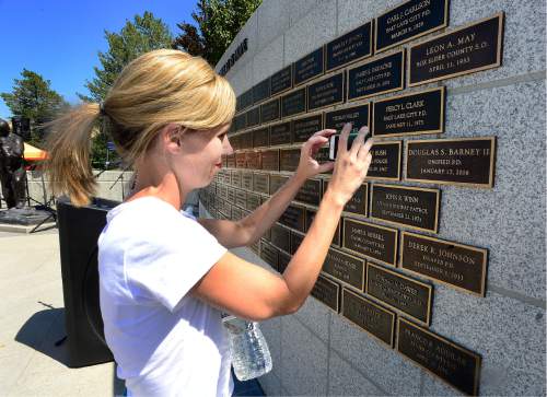 Scott Sommerdorf   |  The Salt Lake Tribune  
Shauna Maddox photographs Officer Doug Barney's plaque at the Utah Law Enforcement Memorial, Sunday, August 21, 2016.