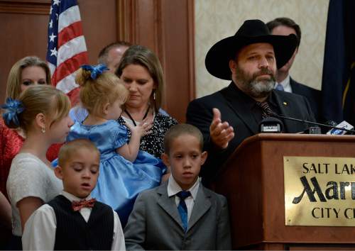 Scott Sommerdorf   |  The Salt Lake Tribune
Rick Koerber speaks at a news conference supported by family. His daughter Bethany is at far left, two adopted sons, Erick and Samuel in the foreground, and his wife Jewel Skousen holds their daughter Annastasia the day after a federal judge tossed out 18 charges against Koerber that had alleged he operated a giant Ponzi scheme through his real estate company, Friday, August 15, 2014.