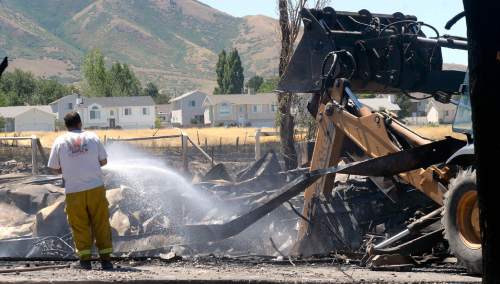 Al Hartmann  |  The Salt Lake Tribune 
Firefighters work to put out hot spots in a burned out mobile home park in Tooele, Utah, on Wednesday, July 20, 2016. Wind whipped up a grass fire that eventually destroyed 10 homes.