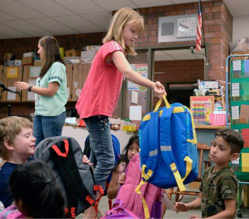 Al Hartmann  |  The Salt Lake Tribune
Alia Leonard hands out a backpack to each student in a kindergarten class at Bennion Elementary School on Wednesday, Aug. 31.  She raised enough money for more than 300 backpacks with school supplies for every student in the school.