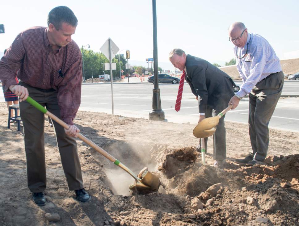 Rick Egan  |  The Salt Lake Tribune
Brett Sawyer UDOT project manager, Rep. Stewart Barlow and Rep Stephen Handy, bury a time capsule, filled with items symbolizing partnerships behind the Hill Field road project, in Layton on Wednesday.