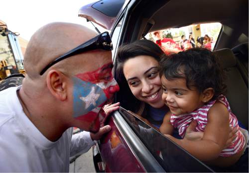 Scott Sommerdorf   |  The Salt Lake Tribune  
Giovani Batista, left, wearing a flag of Puerto Rico in face paint, leans in to kiss his daughter and wife during the first Annual Hispanic Heritage Parade & Street Festival at The Gateway, Saturday, September 3, 2016.