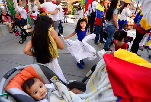 Scott Sommerdorf   |  The Salt Lake Tribune  
Isabella, left, Anastasia, dancing at center, and Denis Ferrer, sitting in the stroller, practice prior to the first Annual Hispanic Heritage Parade & Street Festival at The Gateway, Saturday, September 3, 2016. The Ferrer's were part of the lively Venezuelan contingent.