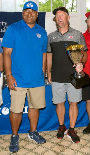 Steve Griffin / The Salt Lake Tribune

University of Utah head coach Kyle Whittingham holds the winning trophy as he stands with BYU head coach Kalani Sitake following the rivalry for charity (National Kidney Foundation) golf tournament at Hidden Valley Country Club in Sandy, Utah Monday June 13, 2016. The tournament pitted the Utah football team coaches against the BYU football coaches with the losing team singing the others fight song. Sitake and his team held up their end of the bargain and sang the University of Utah fight song after falling to the Utah coaches in the tournament.