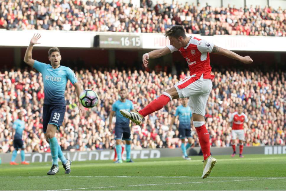 Arsenal's Mesut Ozil, right, scores a goal during the English Premier League soccer match between Arsenal and Swansea City at The Emirates Stadium in London, Saturday Oct. 15, 2016. (AP Photo/Tim Ireland)