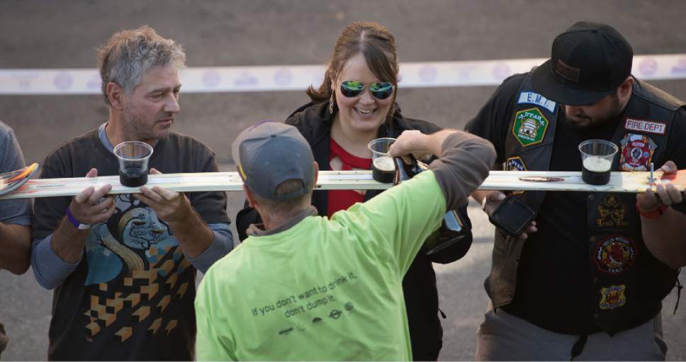 Leah Hogsten  |  The Salt Lake Tribune
Revelers watch as their cups are filled with two ounces of ale. Wasatch Brew Pub in Park City celebrated its 30th anniversary by attempting to break the world "shot-ski" record, Saturday, October 22, 2016. For the attempt, 1,191 people lined up on Main Street to raise one long ski -- 1,961-feet long with glasses attached-- for a shot of Wastach's premium ale.