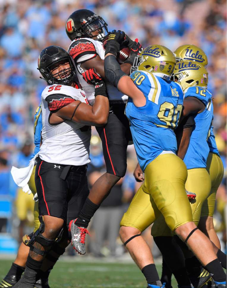 UCLA defensive lineman Rick Wade (90) and linebacker Jayon Brown (12) try to stop Utah running back Joe Williams, second from left, as offensive tackle Sam Tevi supports him during the first half of an NCAA college football game, Saturday, Oct. 22, 2016, in Pasadena, Calif. (AP Photo/Mark J. Terrill)
