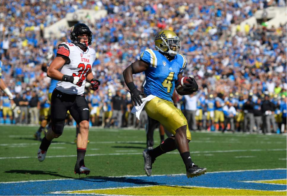 UCLA running back Bolu Olorunfunmi, right, scores a touchdown as Utah linebacker Cody Barton follows during the first half of an NCAA college football game, Saturday, Oct. 22, 2016, in Pasadena, Calif. (AP Photo/Mark J. Terrill)
