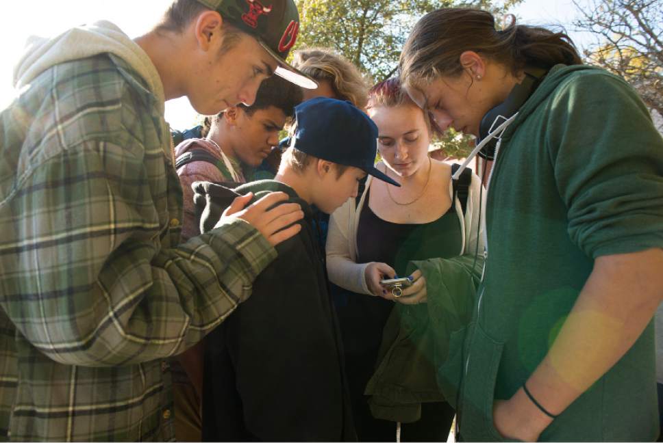 Leah Hogsten  |  The Salt Lake Tribune
Kalani Matthews, 17, right, and his friends gather around Rachel Otteson, 18, as they try to identify the Union Middle School shooting suspect in photographs. A 16-year-old boy was critically injured after being shot outside Union Middle School in Sandy by a 14-year-old, who is a student at the middle school. The shooting occurred about 3 p.m. when two teenage boys got into an argument on a field north of the school, said Sandy police Sgt. Dean Carriger. The victim -- who is a student at Hillcrest High School -- was transported by ambulance in critical condition to Intermountain Medical Center, where he went into surgery about 4:30 p.m. to treat two gunshot wounds. The 14-year-old suspect is in custody.
